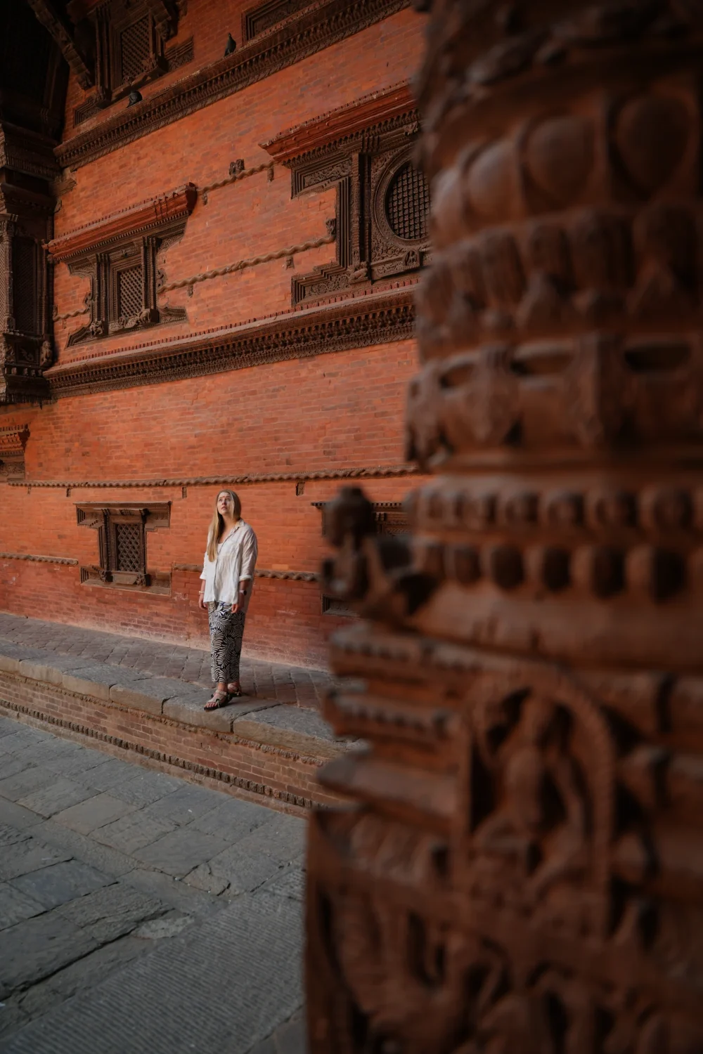 Durbar-Square-Katmandu-Nepal-Drewniane-Miasto-Atrakcje-Co-Robic-Przewodnik-Podrozniczy Kobieta zwiedzająca najlepsza atrakcje Katmandu Durbar Square na tle zdobionej fasady pałacu Hanuman Dhoka przykład newarskiego rzemiosła