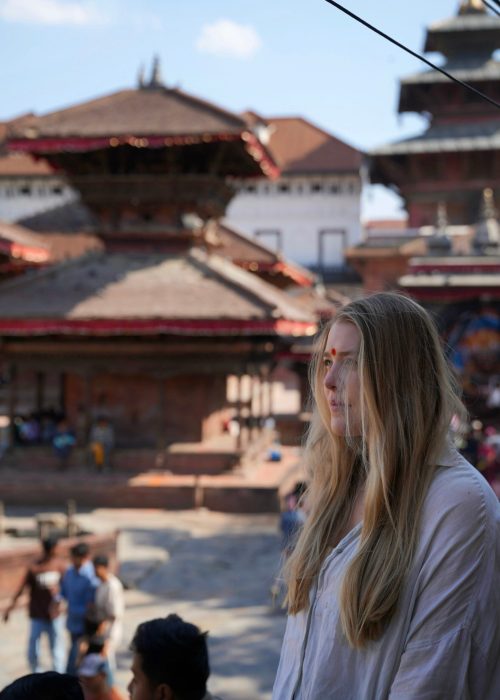 Katmandu-Durbar-Square-Ile-Kosztuje-Wejscie-Bilety-Nepal-Travelbymonkey-Zwiedzanie-Przewodnik-Architektura Podróżniczka Monika z Travel by Monkey na tle tradycyjnych świątyń w Durbar Square, Katmandu